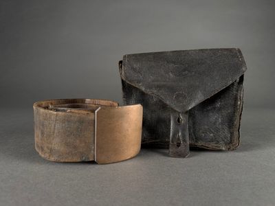 an old leather belt with a metal buckle next to a leather pouch