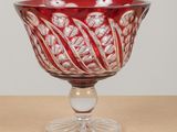 a red glass bowl sitting on top of a wooden table