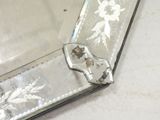 a mirror that has a silver frame with a flower design on it