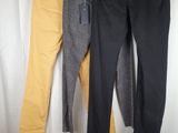 three pairs of black, yellow and grey pants hanging on a clothes rack