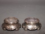 two silver bowls sitting on a table next to each other