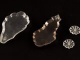 three pieces of clear glass sitting on top of a black surface