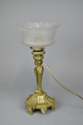 an antique brass table lamp with a frosted glass shade