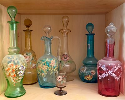 many different colored glass vases on a shelf