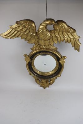 a gold clock with an eagle on it hanging on a wall