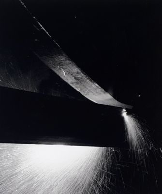 black and white photograph of a person using a large knife to cut a piece of paper
