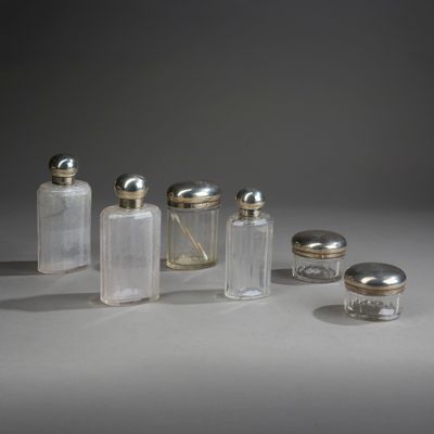 plusieurs bouteilles en verre avec des bouchons argentés, posées sur une surface blanche