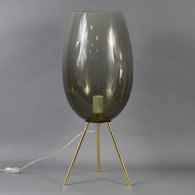 an image of a gray glass lamp with a gold tripod base
