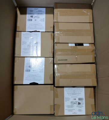 Plusieurs boîtes contenant des appareils électroniques sont empilées dans un carton.