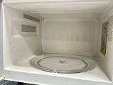 a white microwave that is inside of a white cabinet