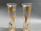 two vases with gold designs on them on a gray surface