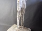 sculpture of a man standing on a rock with a goat on it ' s back