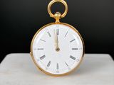 une horloge dorée à chiffres romains posée sur une table en marbre