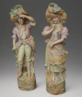 pair of figurines of a woman and a man with hats