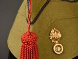 a green hat with a red tassel attached to it