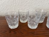 four glasses are lined up on a table with a wall in the background