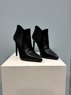 a pair of black leather ankle boots sitting on top of a white box