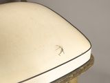 a close up of a white chair with a bug on it