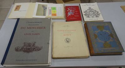 several books are on a table with a chair in the background
