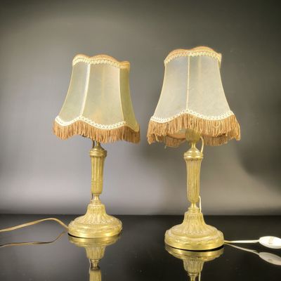 pair of gold table lamps with fringed lampshads on a black table