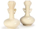 two white vases that are sitting on a table