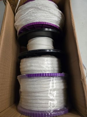 une boîte remplie de cordes blanches et violettes, dans un carton