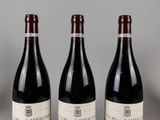 trois bouteilles de vin sont alignées sur une table