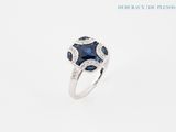 a close up of a ring with a blue sapphire and diamonds