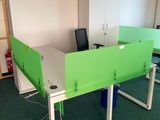 deux bureaux verts dans une pièce recouverte d'une moquette verte