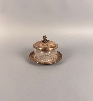 un petit bocal en verre muni d'un couvercle, posé sur une soucoupe