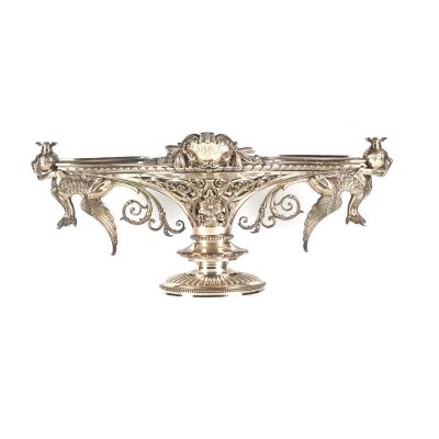 un plat ancien en argent orné d'oiseaux, posé sur un socle