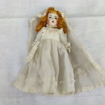 l'image d'une poupée aux cheveux roux et à la robe blanche