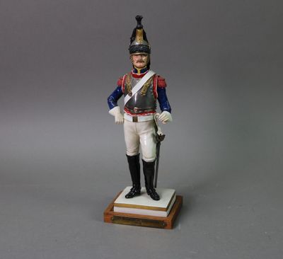 figurine of a man in a uniform with a sword on a wooden base