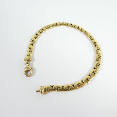 gros plan d'un bracelet en or sur une surface blanche