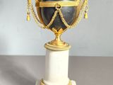 a black and gold vase sitting on a marble base