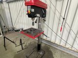 une perceuse rouge et noire dans un garage, avec un tuyau bleu