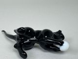 a black cat laying on its back with a white ball in it ' s mouth