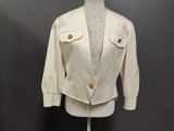 a white jacket on a mannequin stand in front of a gray wall