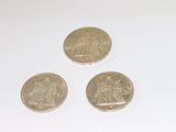 three coins are sitting on a white surface next to each other