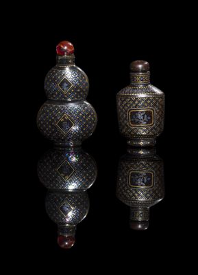 two silver vases sitting next to each other on a black surface