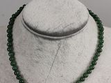 a green jade beaded necklace on a white mannequin