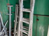 many old ladders leaning up against a green wall