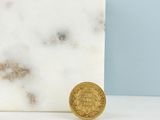 une pièce d'or posée à côté d'un bloc de marbre blanc