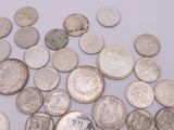 a pile of old silver coins on a white surface