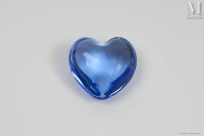 un objet en verre bleu en forme de cœur posé sur une surface blanche