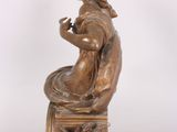 bronze statue of a woman sitting on a stool with a bird in her hand