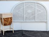 a wicker basket sitting next to a white rattan headboard