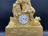 une statue en or représentant un homme assis sur une table, avec une horloge