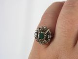 an image of a woman ' s hand holding a ring with a green stone