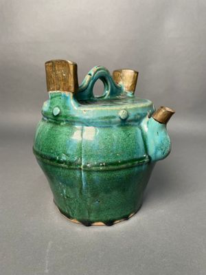 a green teapot with a wooden handle on a table